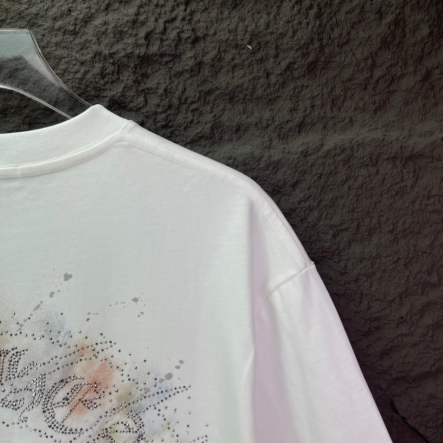 White T-shirt sleeve and back detail with rhinestone script graphic