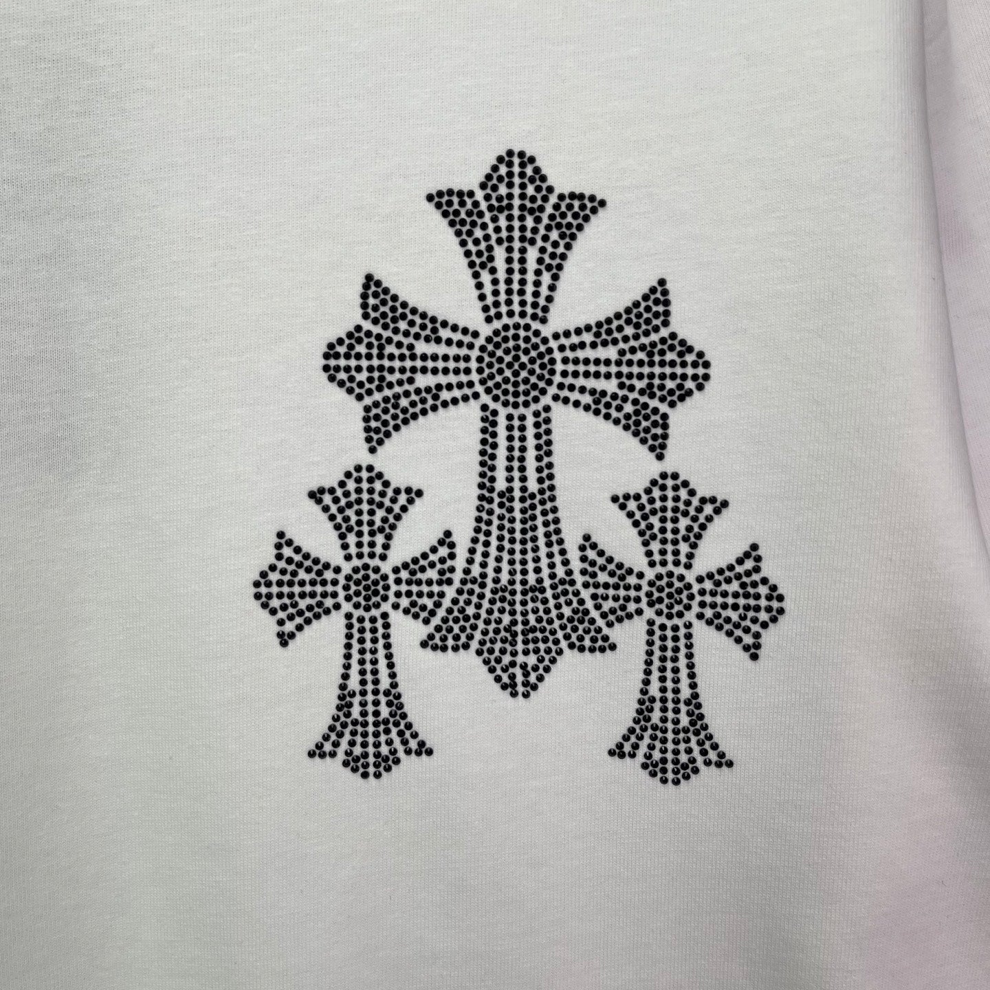 White T-shirt fabric close-up of black cross-studded graphic