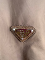 PRADA triangular logo patch on brown jacket with studded leather trim