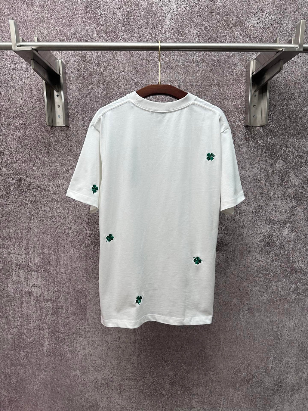 White short-sleeve T-shirt with scattered green clover patches, crew neckline