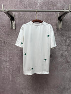 White short-sleeve T-shirt with scattered green clover patches, crew neckline