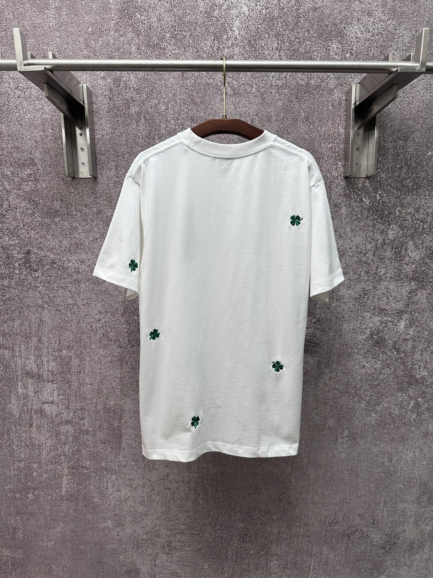 White short-sleeve T-shirt with scattered green clover patches, crew neckline