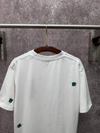 White back of T-shirt with green clover embroidery near hem and sleeves