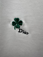 Green four-leaf clover and black Dior logo embroidery on white fabric