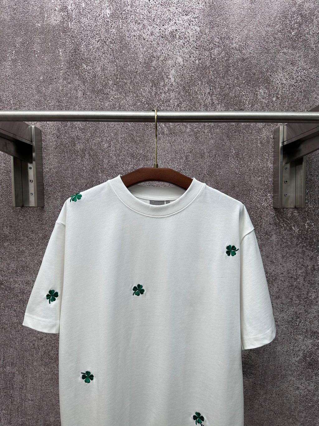 White crew-neck T-shirt with green clover embroidery on chest and sleeves