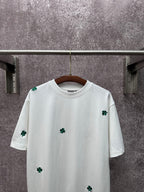 White crew-neck T-shirt with green clover embroidery on chest and sleeves
