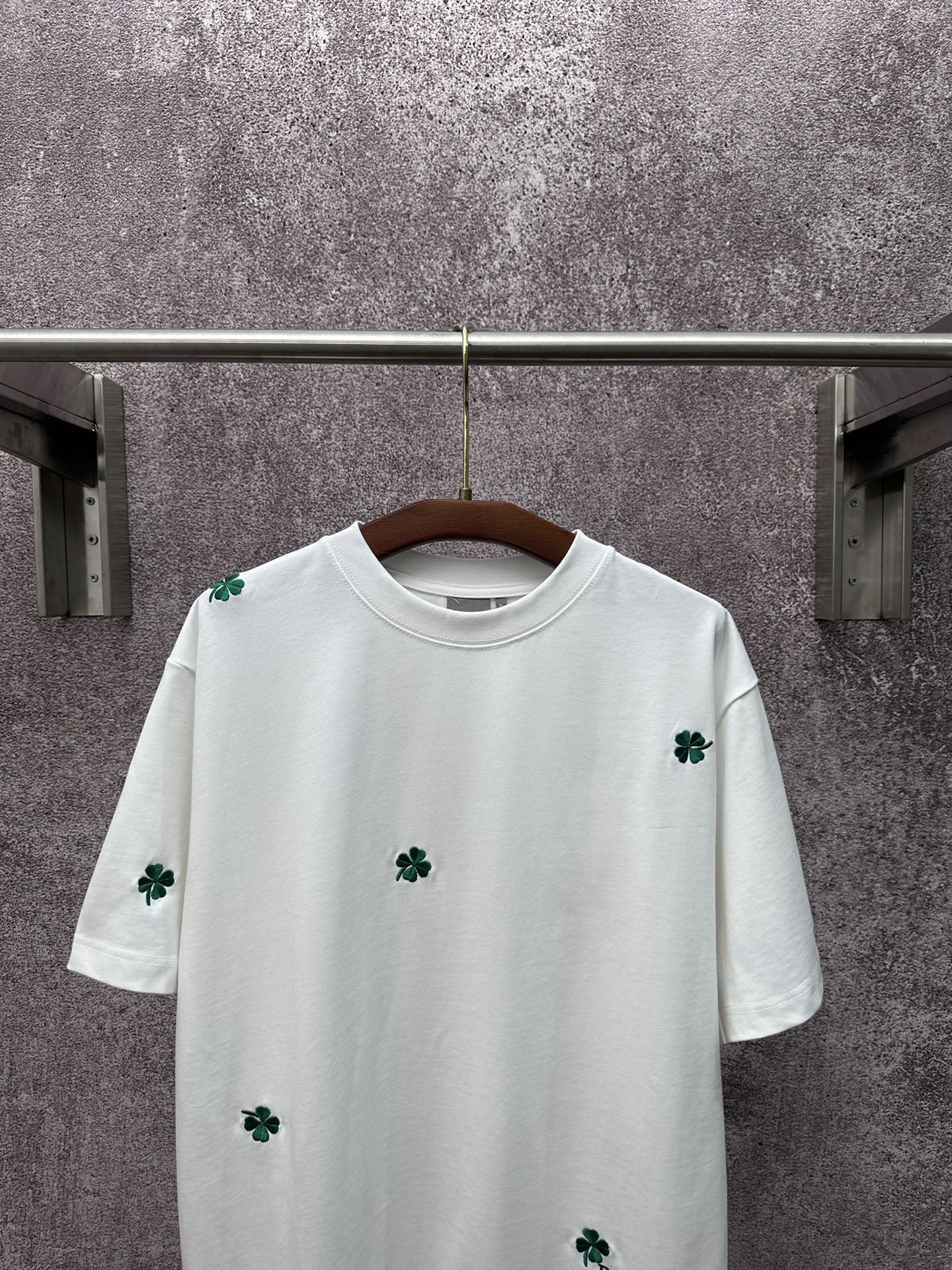 White crew-neck T-shirt with green clover embroidery on chest and sleeves