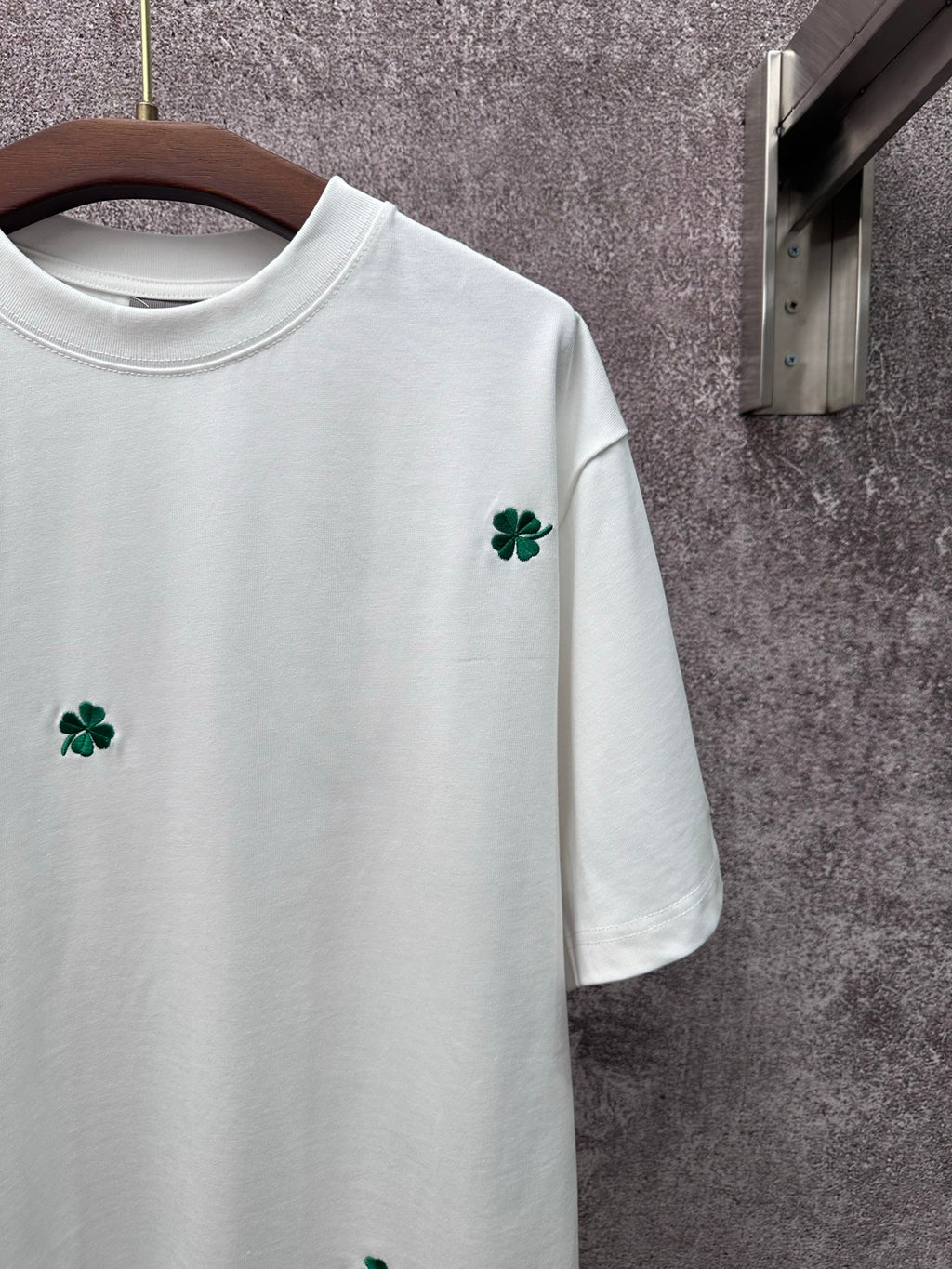 White T-shirt close-up: green clover embroidery on the right chest
