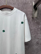 White T-shirt close-up: green clover embroidery on the right chest