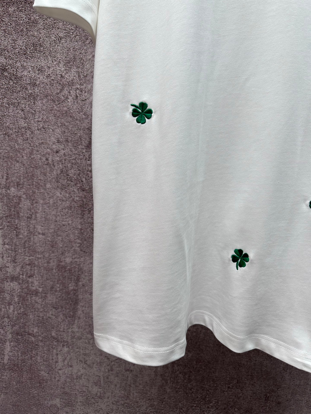 White T-shirt bottom with green clover embroidery at left side