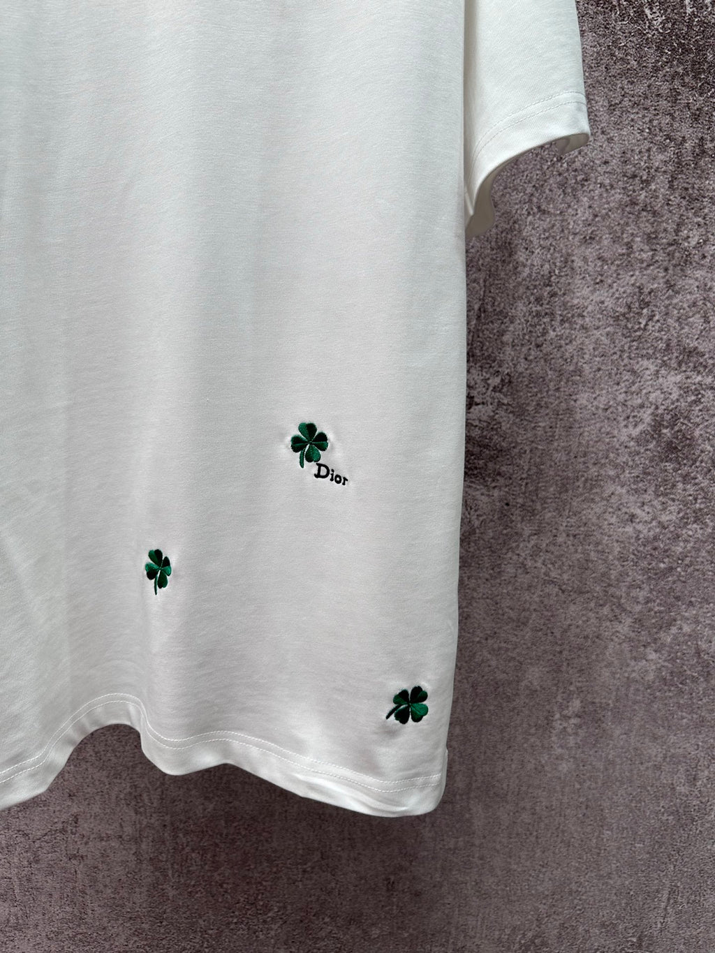 White T-shirt hem with green clover embroidery and small Dior logo detail