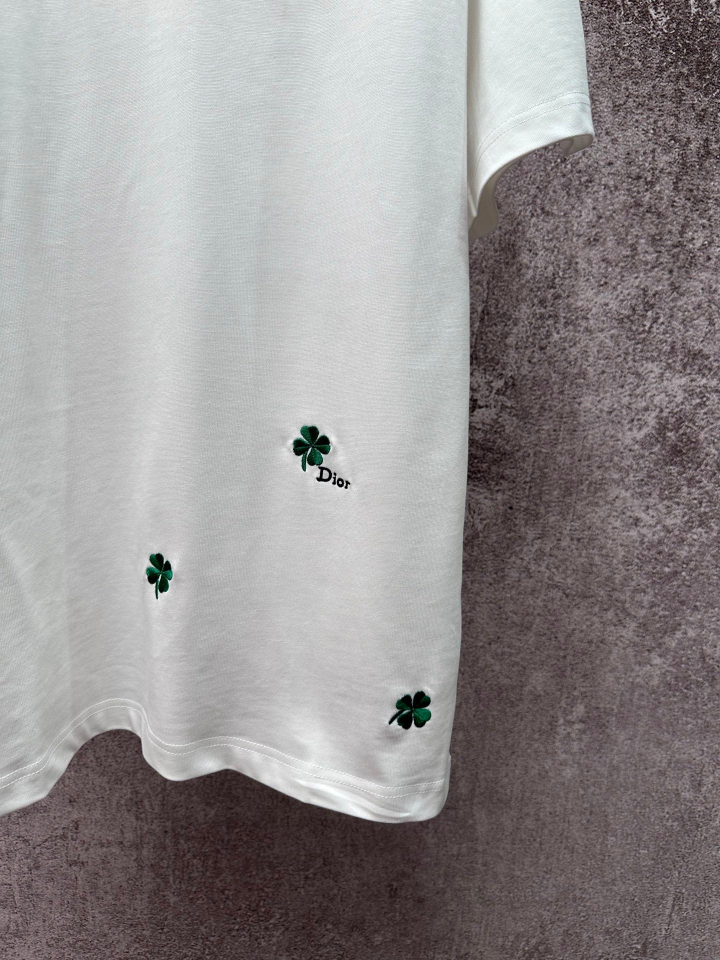 White T-shirt hem with green clover embroidery and small Dior logo detail