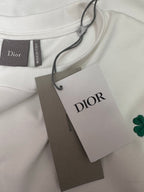 White T-shirt with Dior tag and green clover patch on fabric neckline