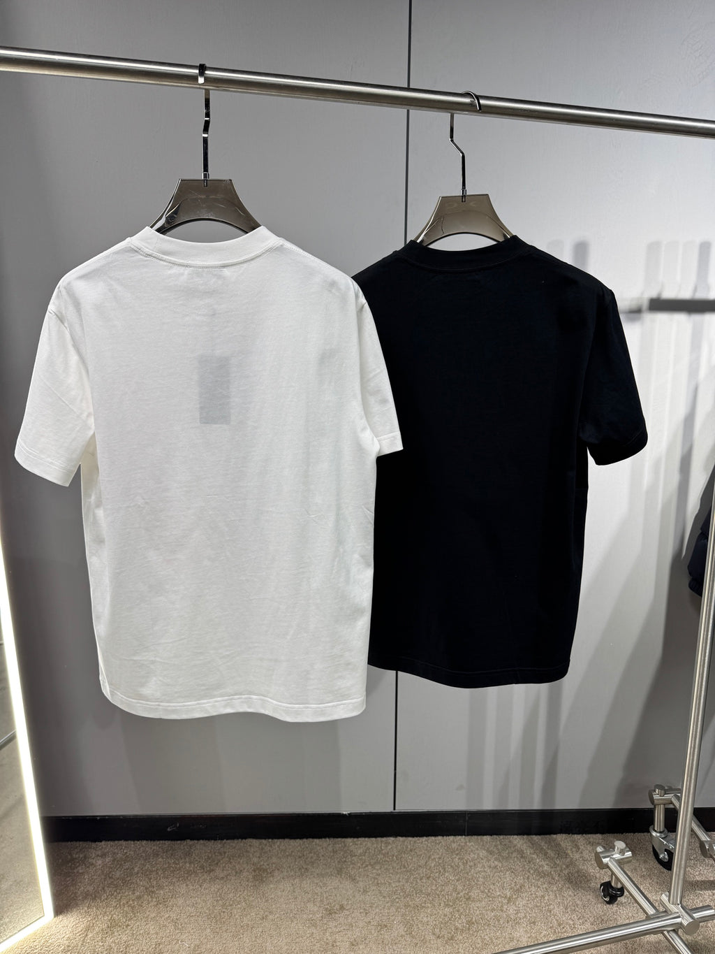 Back view of white and black Versace crewneck T-shirts on hangers