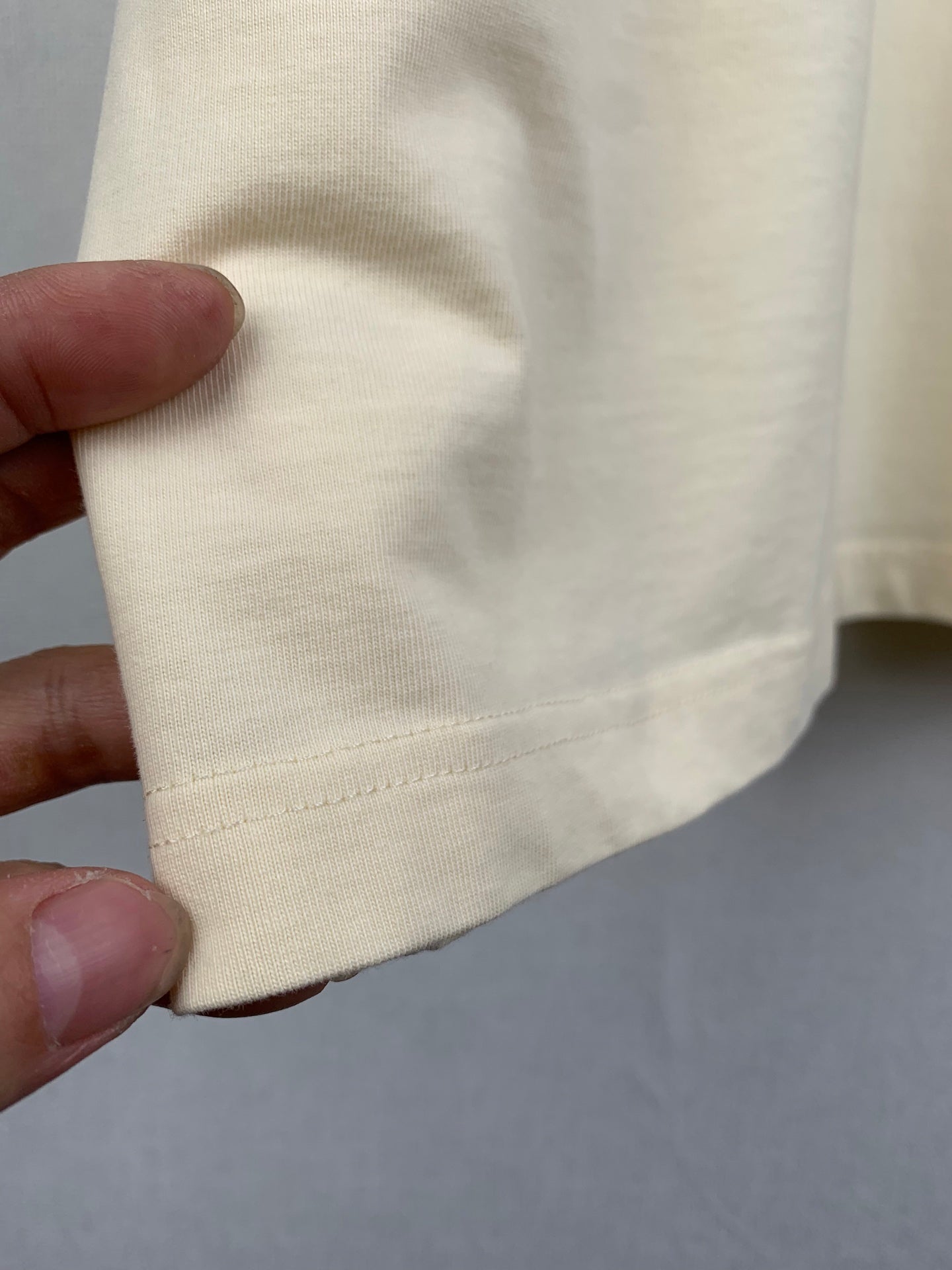 Light yellow Balenciaga T-shirt fabric and hem stitching close-up