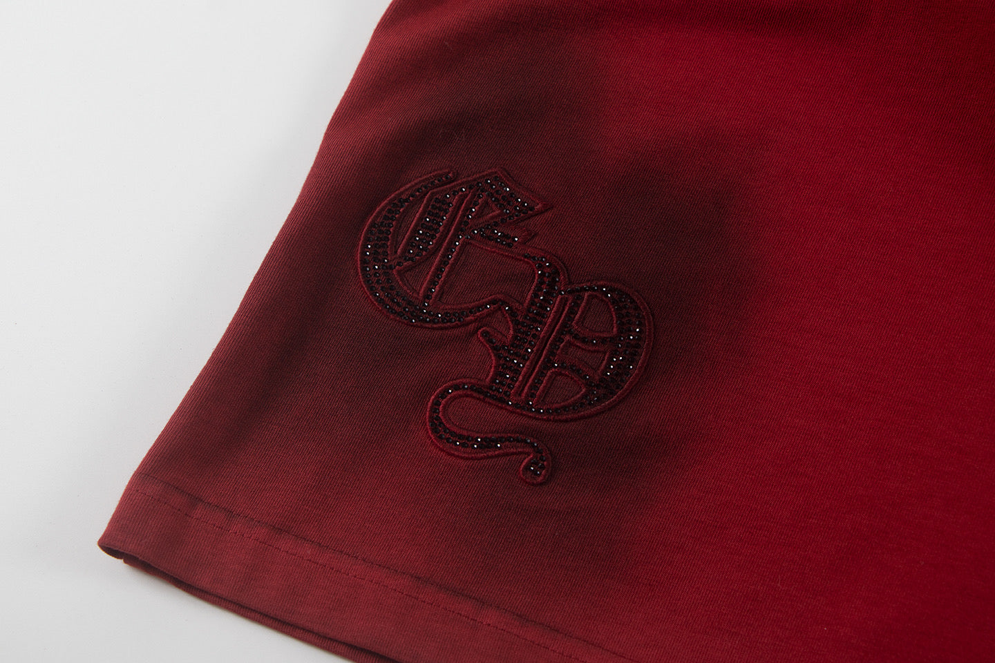 Burgundy T-shirt sleeve with rhinestone-style monogram patch