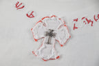 White heart appliqué with red trim and cross motif on a white T-shirt