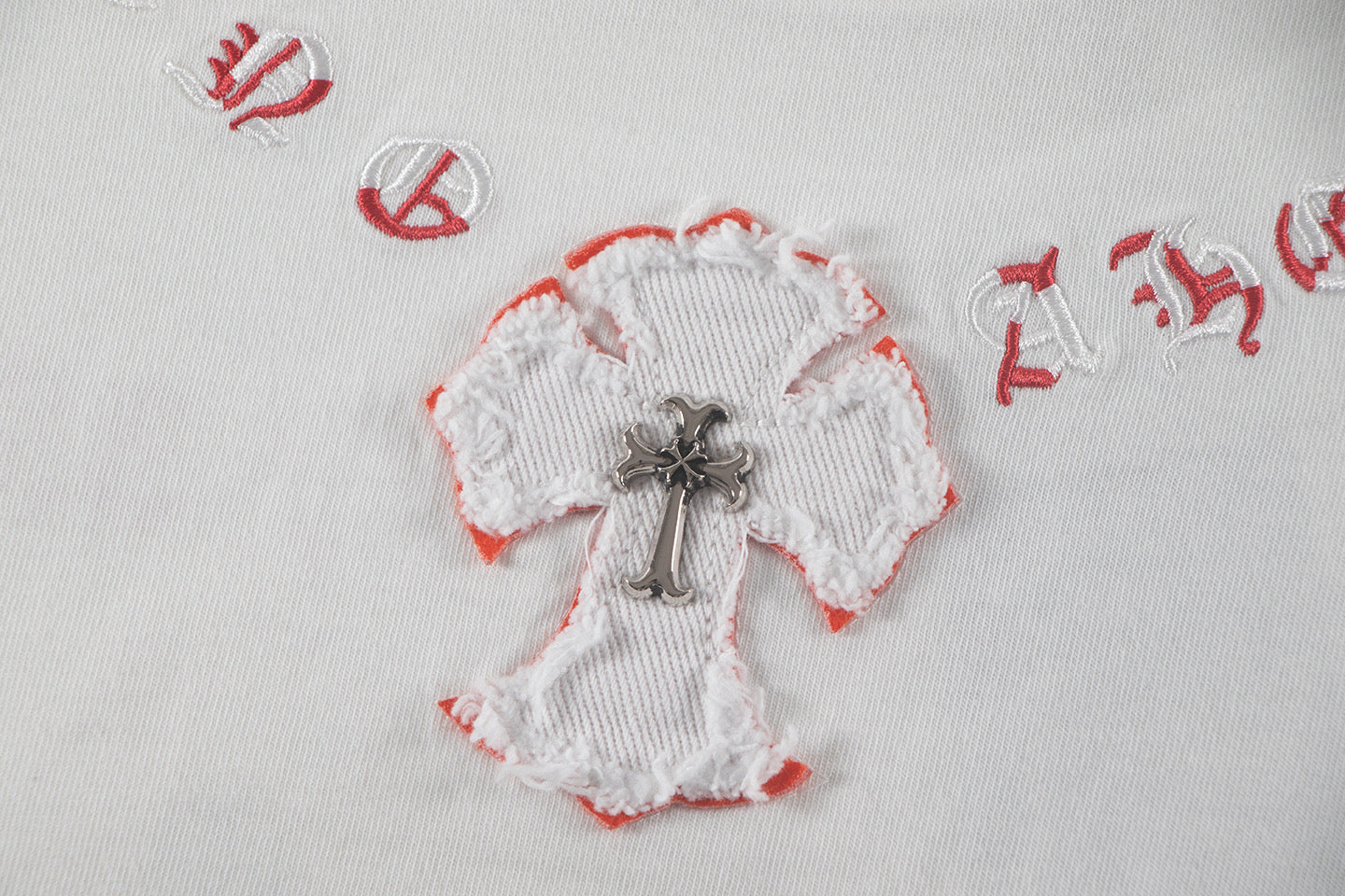 White heart appliqué with red trim and cross motif on a white T-shirt