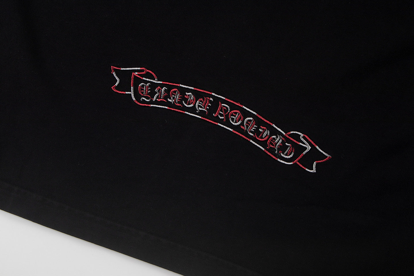 Black T-shirt front detail with red outlined banner graphic