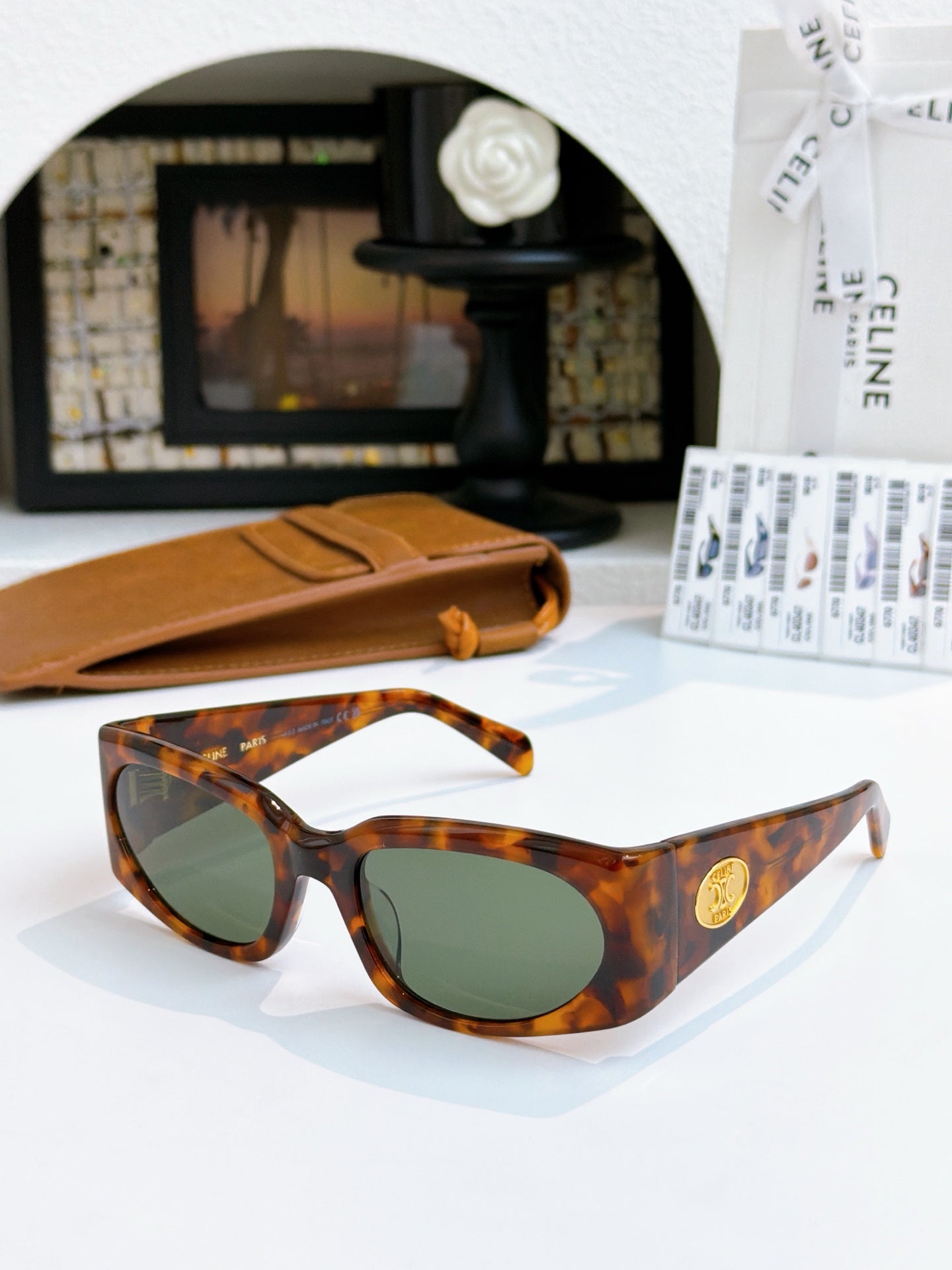 Tortoiseshell sunglasses with green-tinted lenses and gold-tone side medallion.