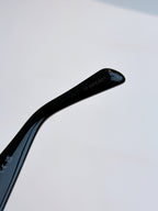 Black sunglasses temple with printed brand text and glossy finish.