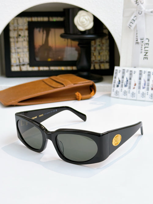 Black oversized sunglasses with dark lenses and gold-tone logo emblem.