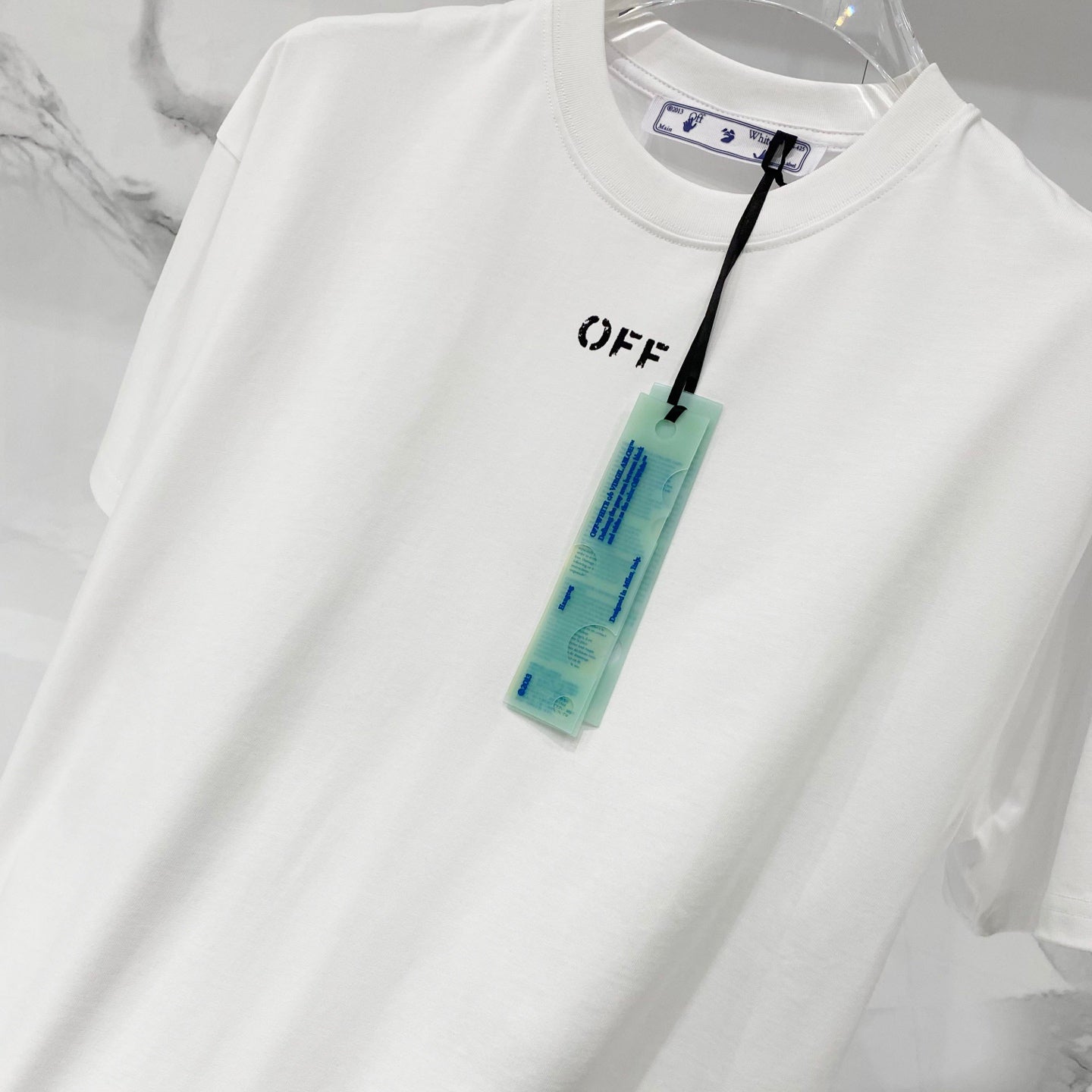 Off-white T-shirt with OFF logo and blue care tag on front
