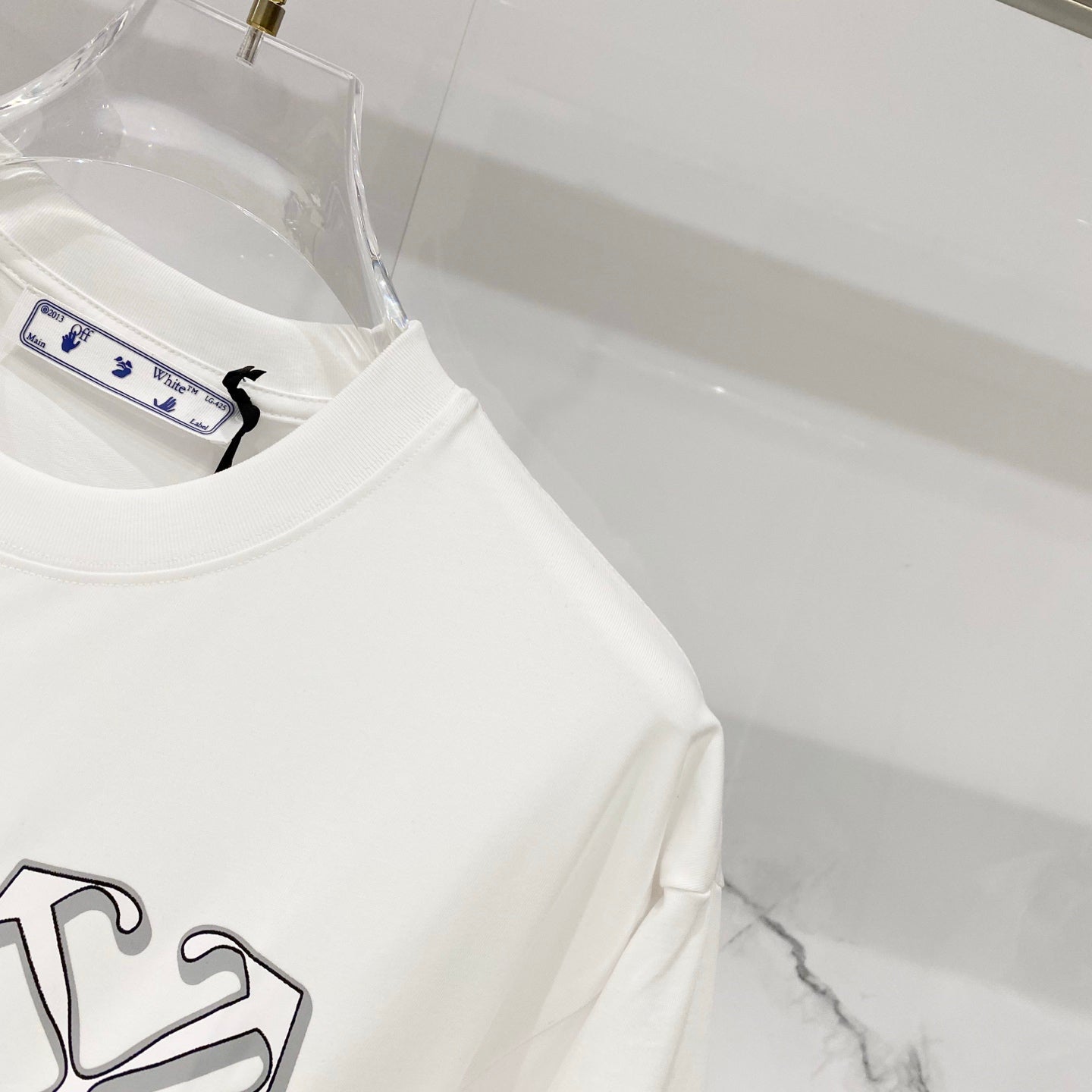 Off-white T-shirt side view with partial emblem and neck label