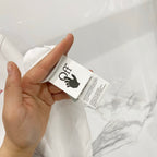 Off-White T-shirt care label and size tag shown on off-white fabric