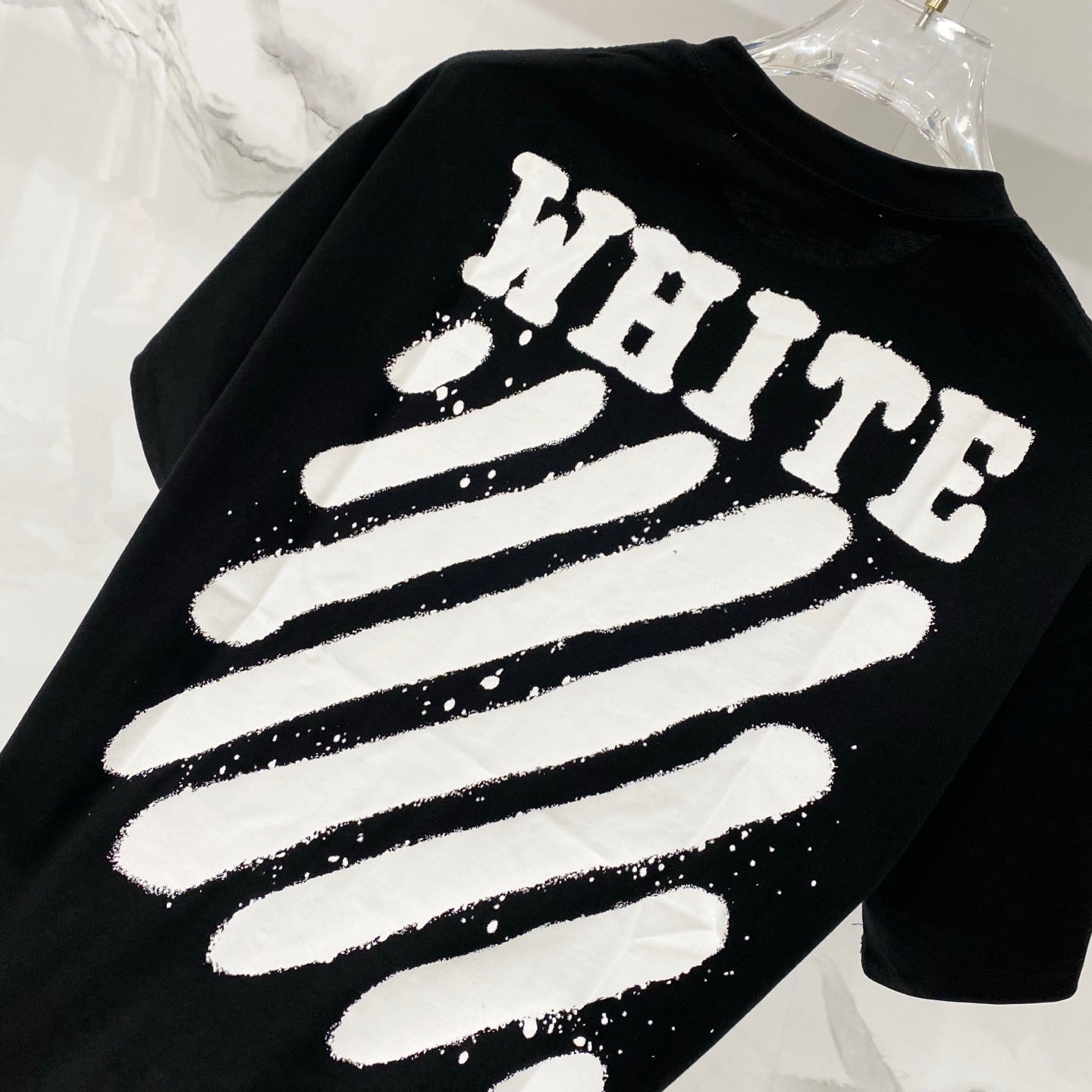 Black T-shirt closeup with 'WHITE' striped graphic print