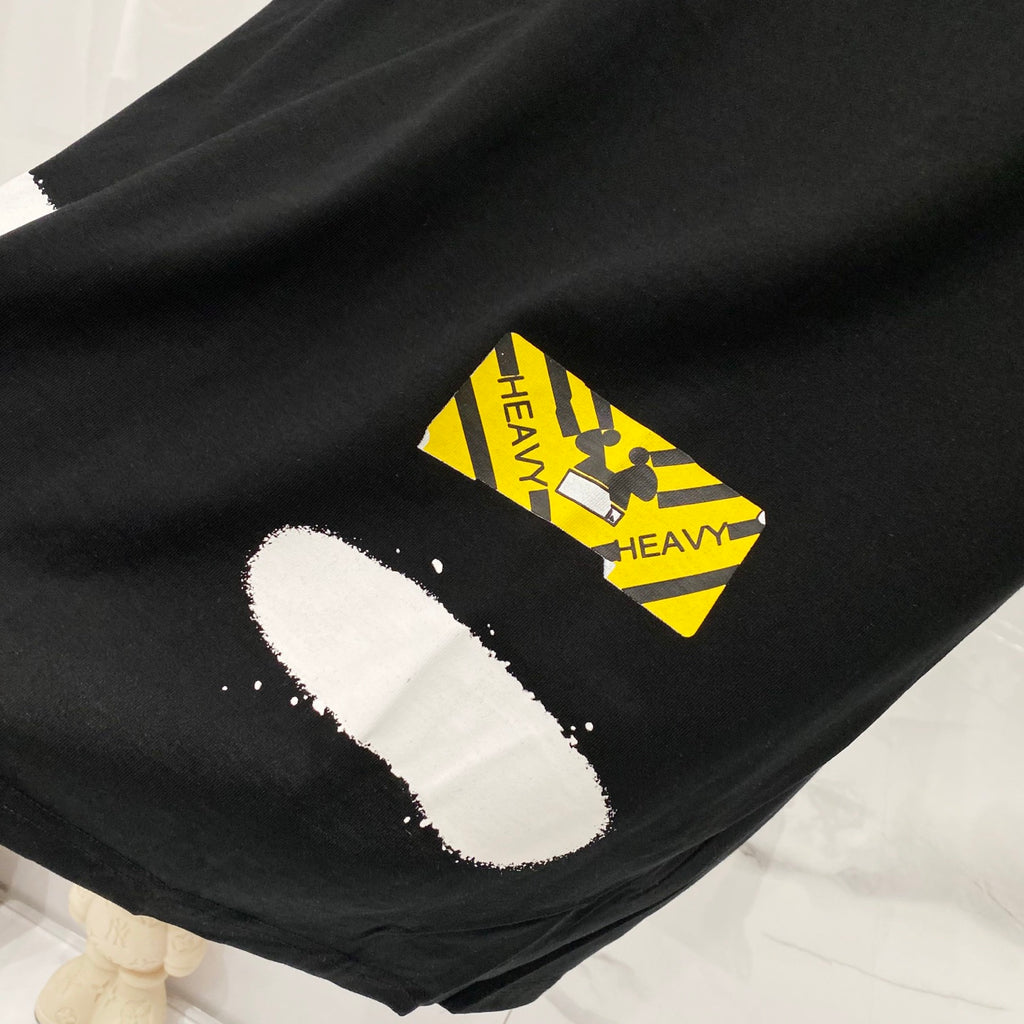 Black T-shirt hem with yellow and white triangular logo graphic