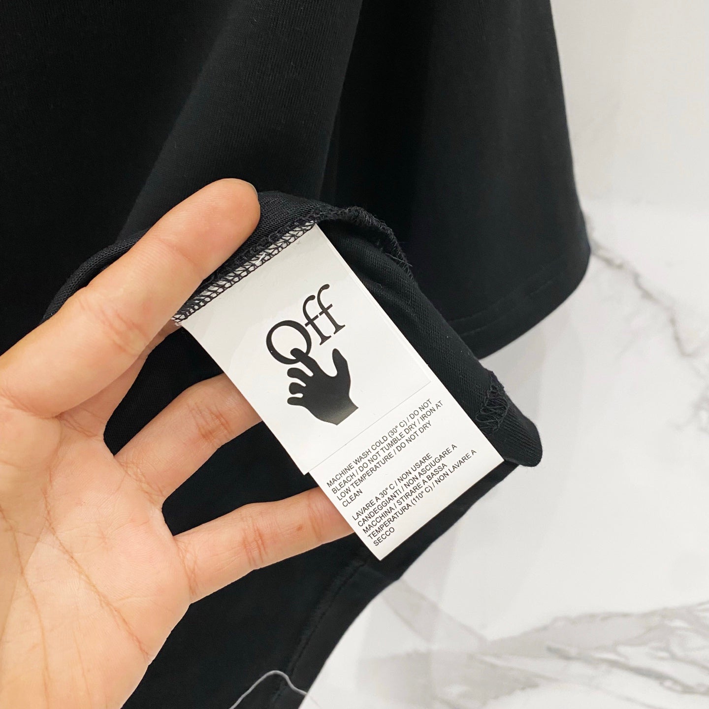 Black T-shirt care label tag held in hand