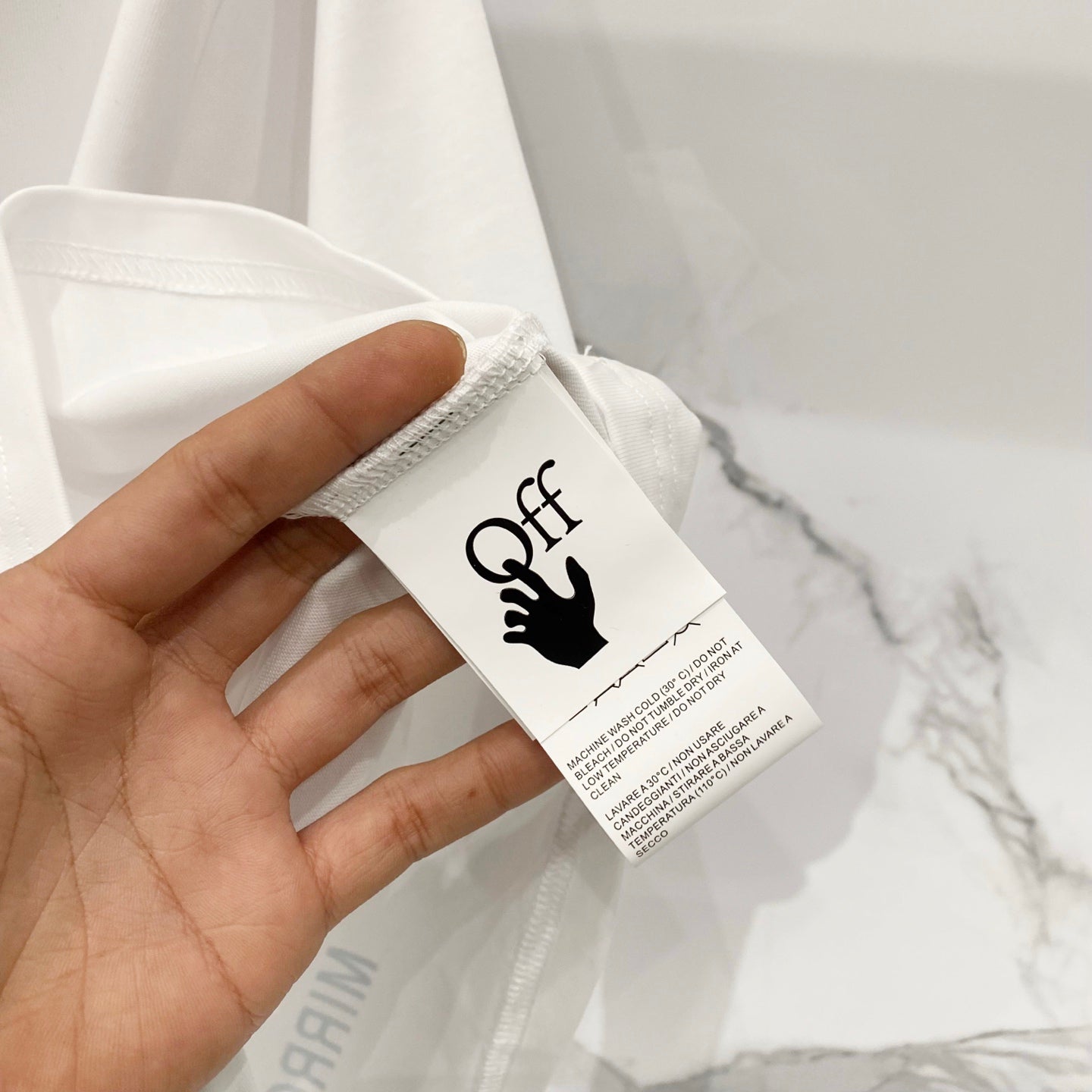 White T-shirt with sewn fabric tag near sleeve seam and small logo text
