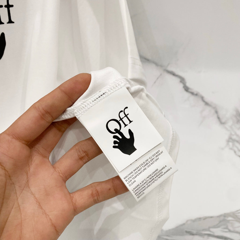 Off-white t-shirt fabric and attached white size/brand care tag.