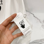 Off-white t-shirt fabric and attached white size/brand care tag.