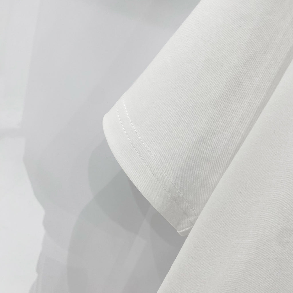 Off-white t-shirt sleeve and hem close-up with visible stitching.