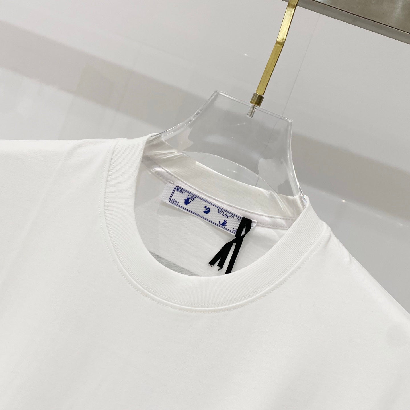 Off-white t-shirt neckline and collar seam, with small inner care label visible.