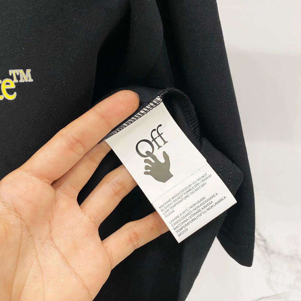Black T-shirt fabric tag with Off-White logo and text.
