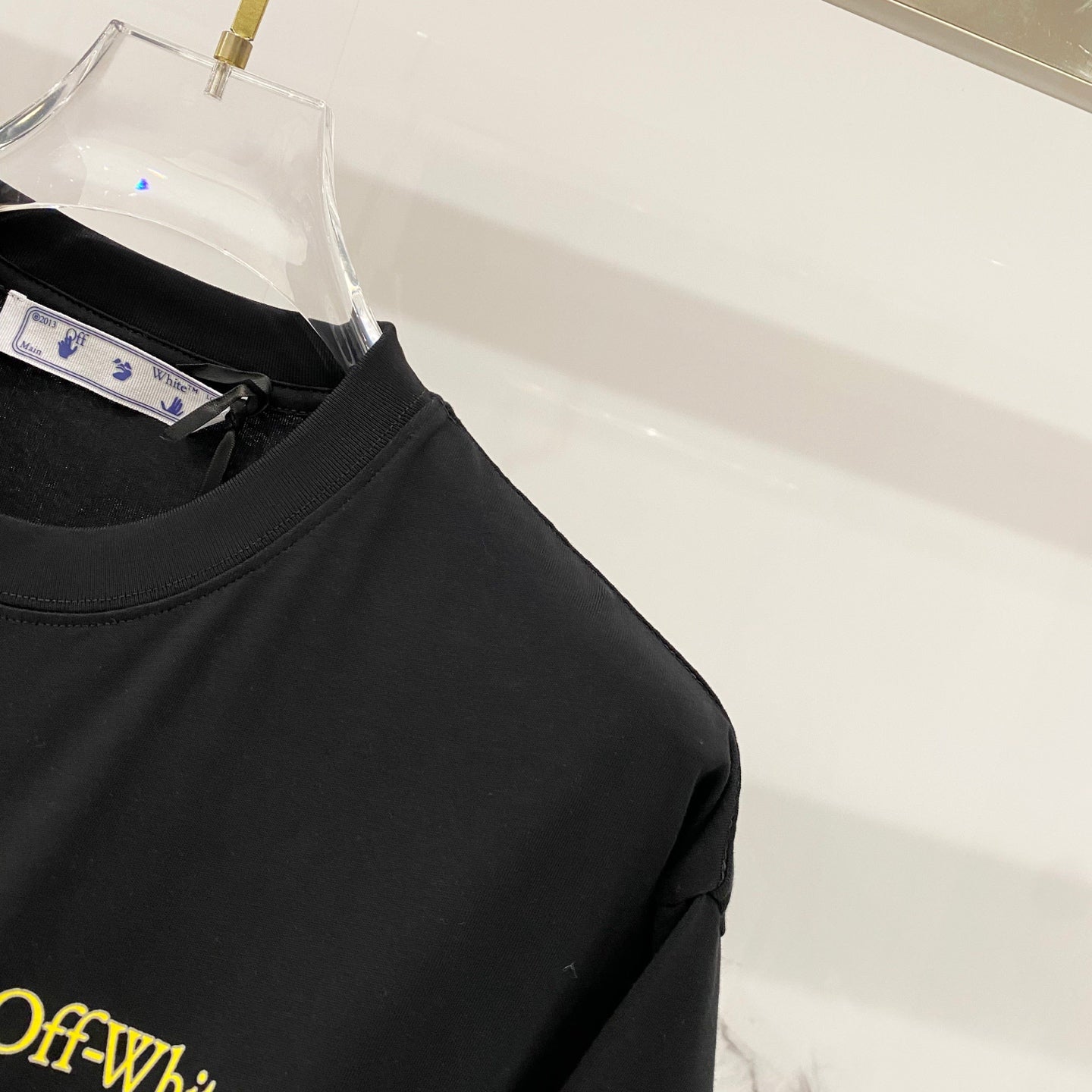Black T-shirt sleeve and neckline with Off-White neck tag.