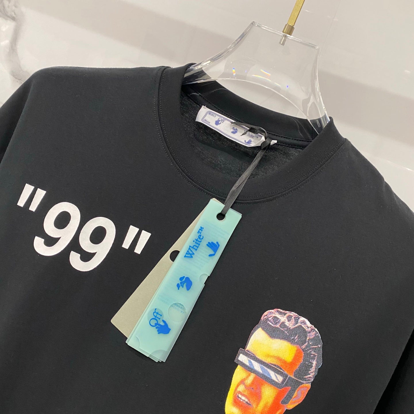 Off-White black T-shirt with '99' quote and portrait graphic print, on hanger