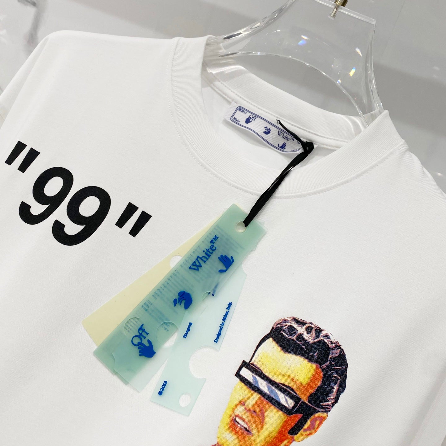 Off-white T-shirt with partial '99' text and colorful face graphic near hem