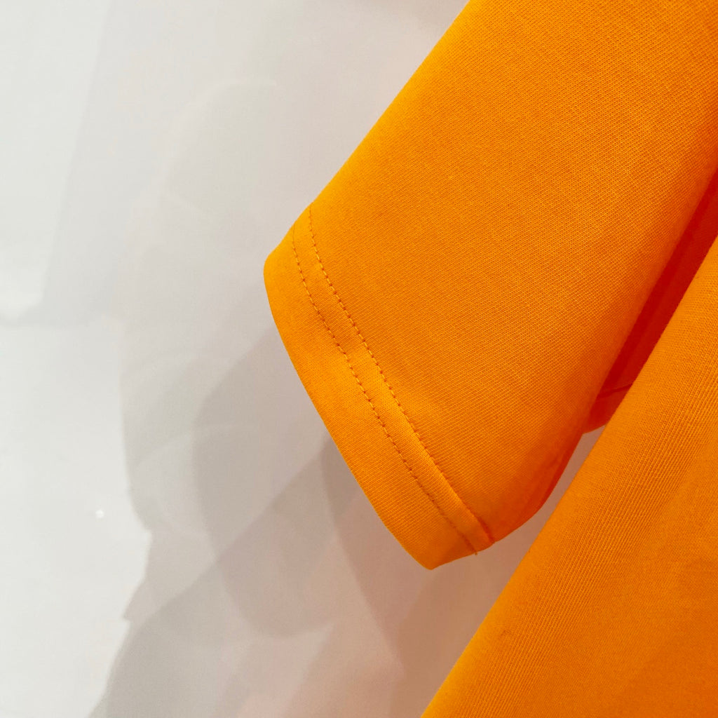 Orange T-shirt sleeve cuff and side seam close-up
