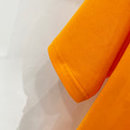 Orange T-shirt sleeve cuff and side seam close-up