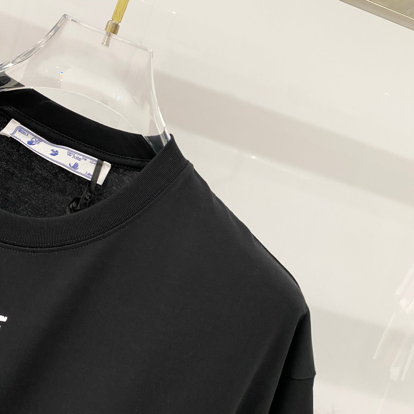 Off-White T-shirt upper front close-up, black crew neck and partial OFF print
