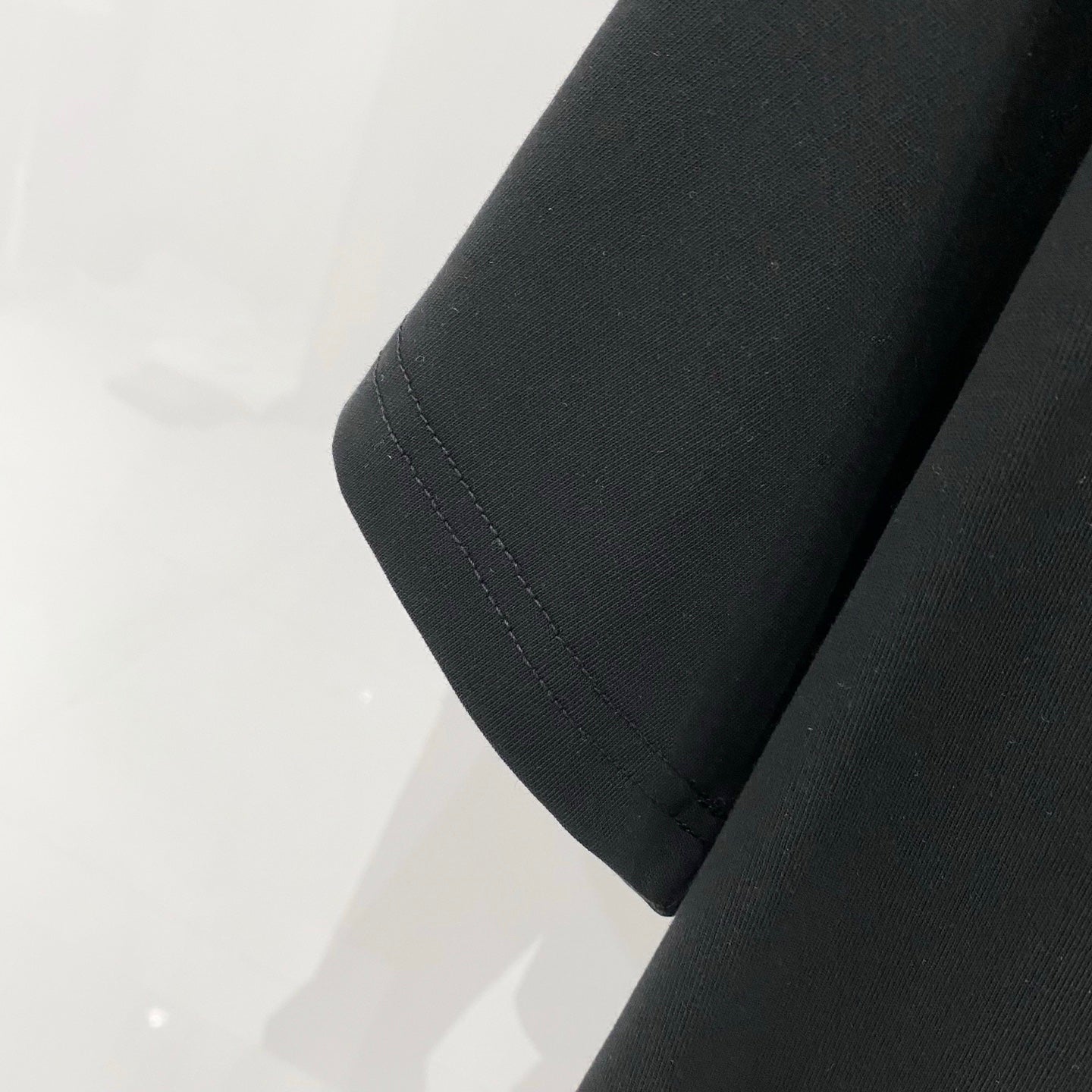 Off-White T-shirt sleeve and side seam close-up, black knit fabric