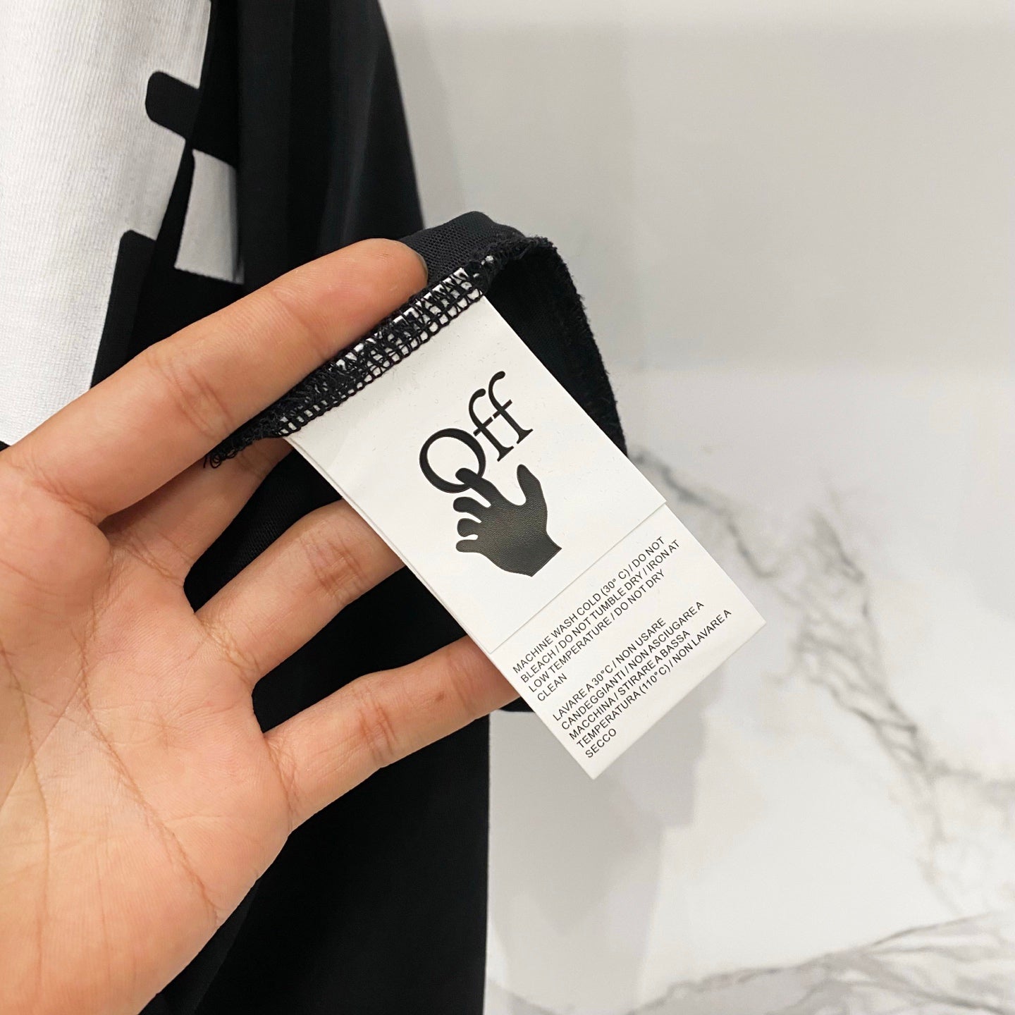 Off White T-shirt care label tag held in hand