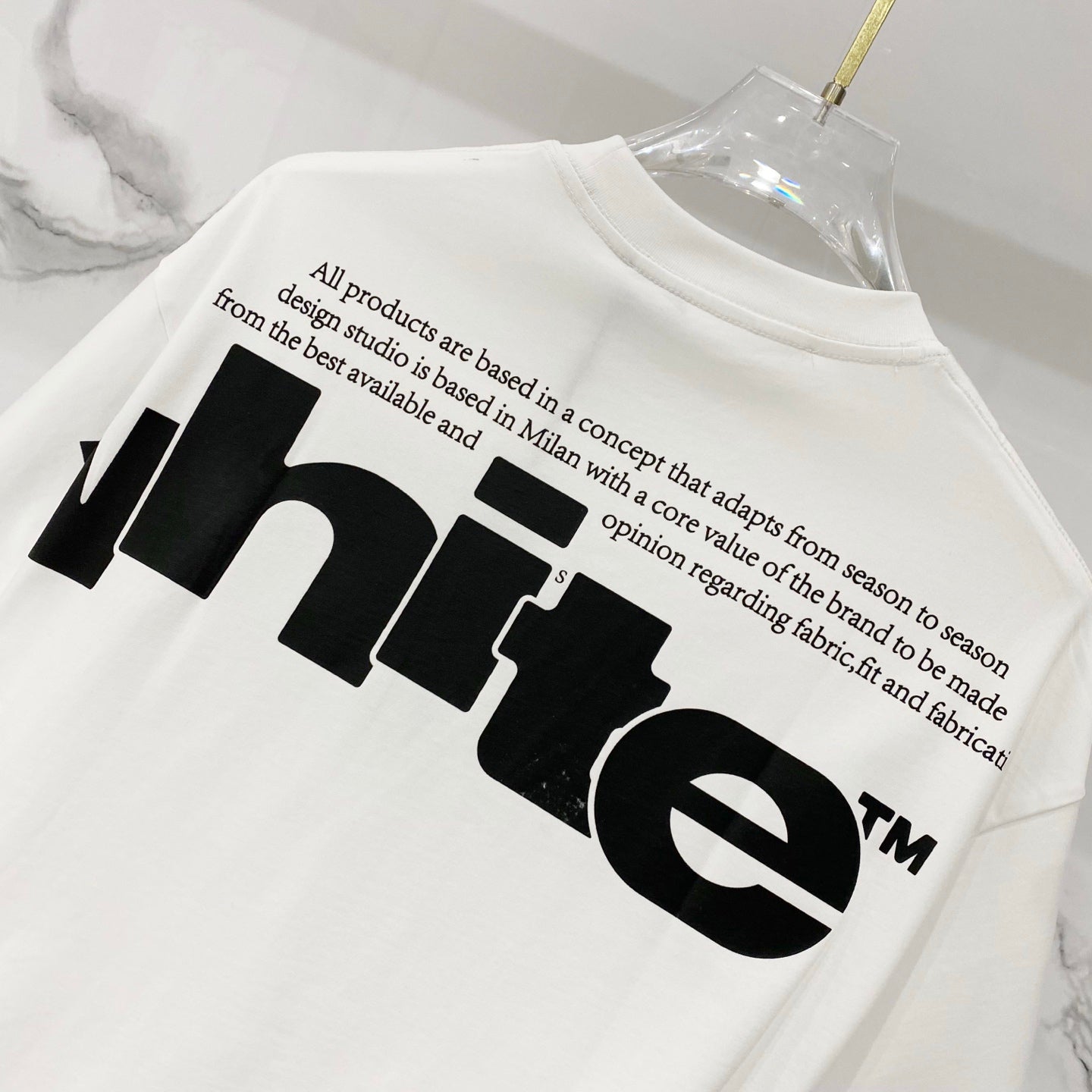 Off White T-shirt with black "WHITE" graphic and small slogan text on back