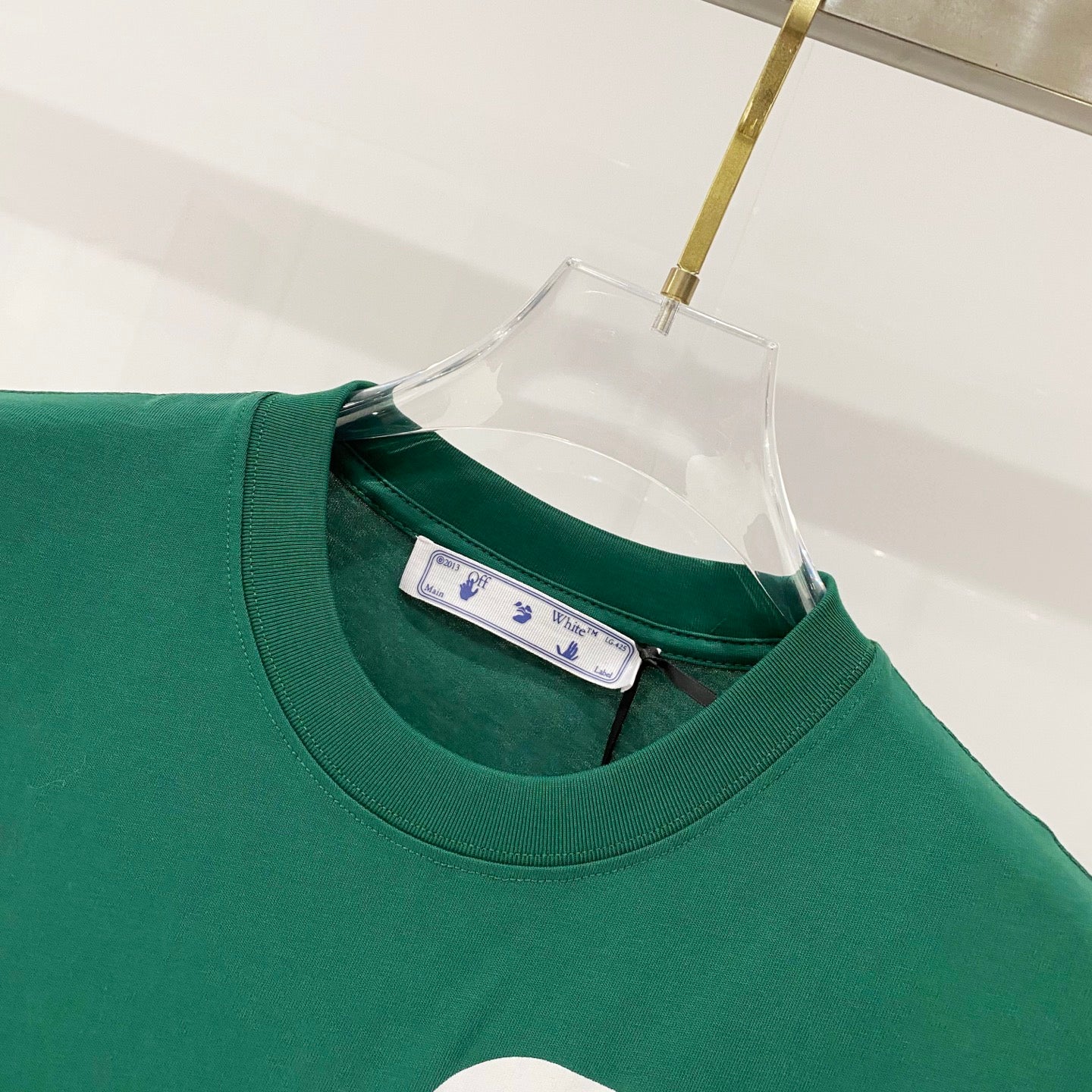 Off-White T-shirt neckline close-up, dark green knit and printed inner label.