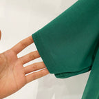 Off-White T-shirt cuff detail, dark green fabric with visible stitching edge.