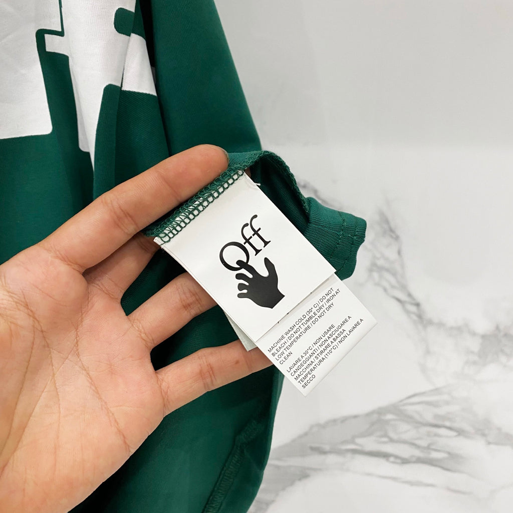 Off-White T-shirt side close-up with white care tag and dark green fabric.